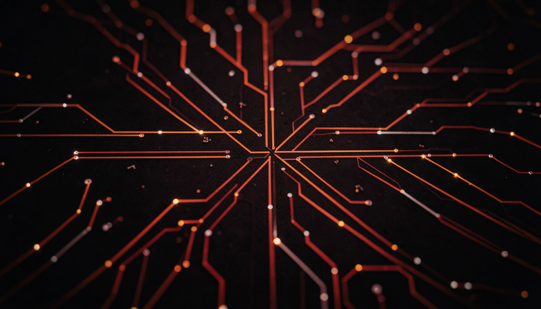 A top-down view of interconnected circuit-like pathways on a dark surface, subtle orange and white highlights tracing the routes